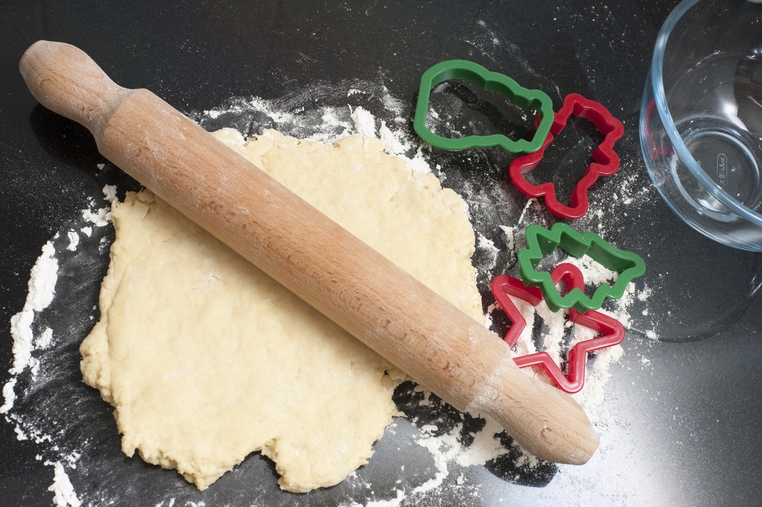Utkavling av pepparkaksdeg med julformar och en glasskål bredvid, en inspirerande scen som passar perfekt för ett säsongsbetonat nyhetsbrev om bakning.